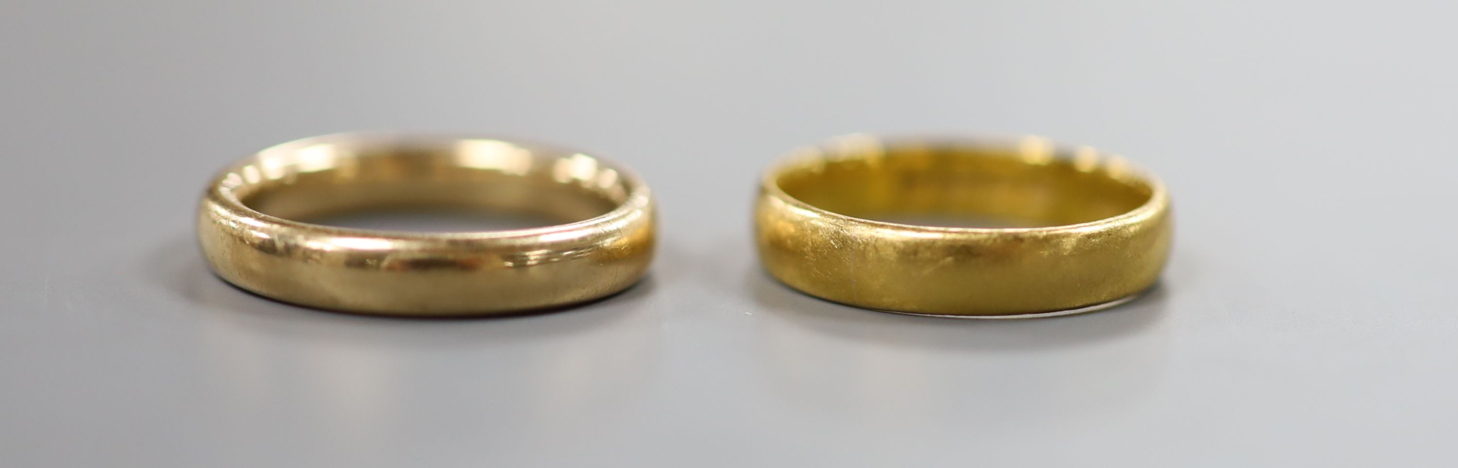 A 22ct god wedding band, 3.7 grams, a yellow meta wedding band, 5 grams and a modern 9ct gold cross pendant on a fine link chain, gross 2.1 grams.